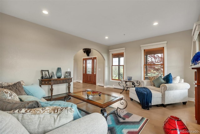 living room featuring arched walkways, wood finished floors, a baseboard heating unit, baseboards, and recessed lighting