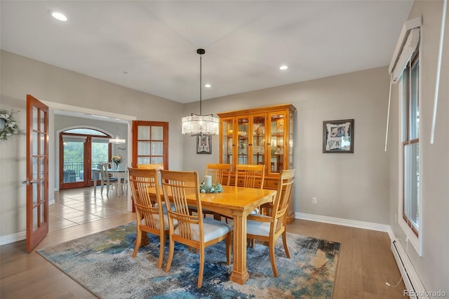dining space with french doors, a baseboard heating unit, wood finished floors, baseboards, and recessed lighting
