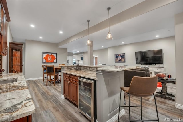 kitchen featuring wine cooler, light wood finished floors, open floor plan, recessed lighting, and a kitchen breakfast bar