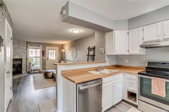 1068 Milo Cir Unit A, Lafayette, CO 80026 - kitchen featuring appliances with stainless steel finishes, under cabinet range hood, open floor plan, a peninsula, and light wood-style flooring