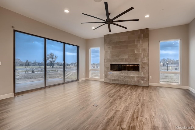 unfurnished living room featuring ceiling fan, plenty of natural light, hardwood / wood-style floors, and a fireplace