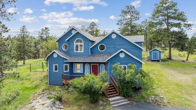 5939 S Skyline Dr, Evergreen, CO 80439 - view of front of house with a storage unit, a shingled roof, a wooden deck, and a front yard
