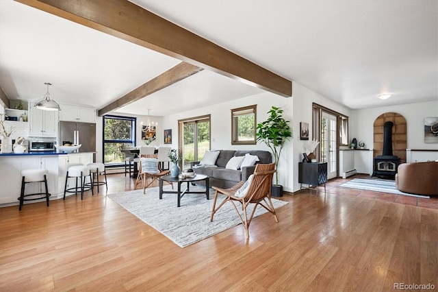 5939 S Skyline Dr, Evergreen, CO 80439 - living area with a wood stove, light wood-style flooring, beam ceiling, a chandelier, and a baseboard radiator