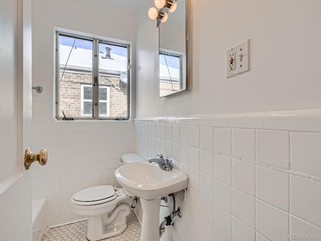 bathroom with tile patterned floors, a healthy amount of sunlight, tile walls, and toilet