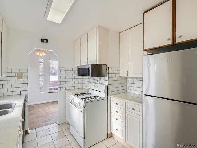 kitchen with light tile patterned flooring, white cabinetry, and appliances with stainless steel finishes