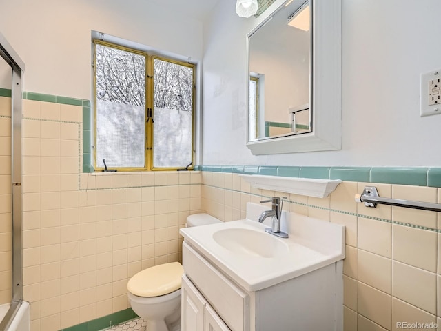 bathroom with vanity, toilet, and tile walls