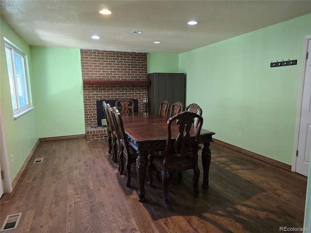 dining room featuring a textured ceiling, a fireplace, and dark hardwood / wood-style flooring