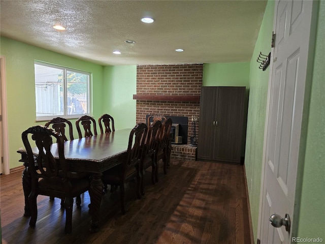 dining space featuring a textured ceiling, a fireplace, and dark hardwood / wood-style flooring