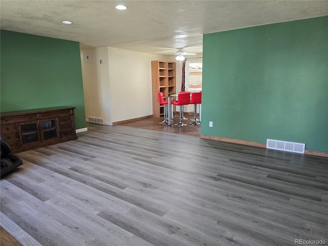 living room featuring a textured ceiling, hardwood / wood-style flooring, and ceiling fan