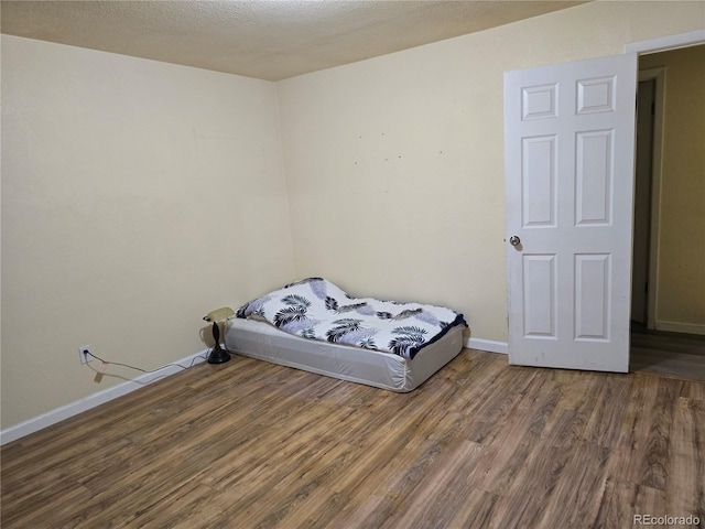 bedroom featuring a textured ceiling and dark hardwood / wood-style flooring