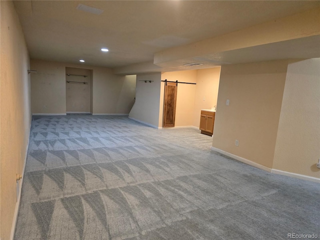 unfurnished room with light colored carpet and a barn door