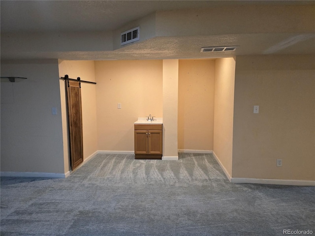 empty room featuring a textured ceiling, carpet floors, and a barn door