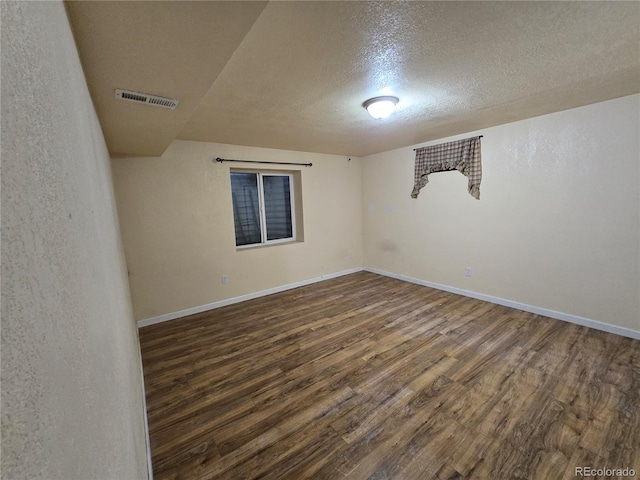 unfurnished room with a textured ceiling and dark hardwood / wood-style floors