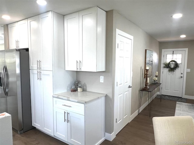 kitchen featuring light stone countertops, white cabinets, dark hardwood / wood-style flooring, and stainless steel fridge with ice dispenser