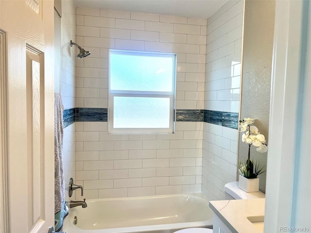 full bathroom with tiled shower / bath, vanity, and toilet