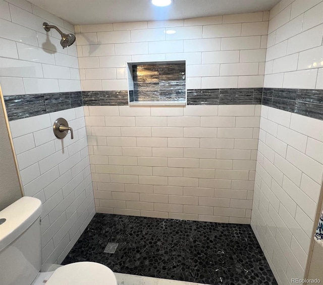 bathroom featuring a tile shower and toilet