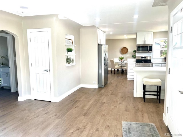 kitchen featuring white cabinets, a kitchen breakfast bar, stainless steel appliances, and light hardwood / wood-style flooring