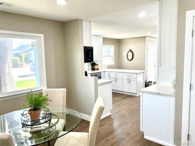 dining area with a wealth of natural light and hardwood / wood-style flooring