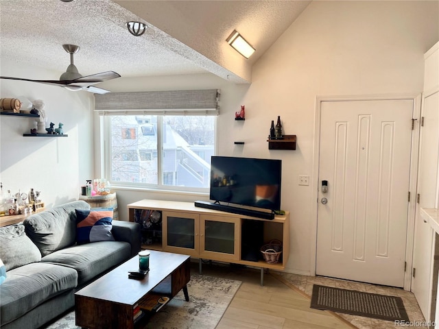 living room with vaulted ceiling, ceiling fan, light hardwood / wood-style floors, and a textured ceiling