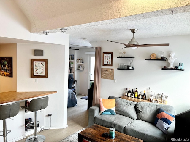 living room with bar area, a textured ceiling, and light wood-type flooring