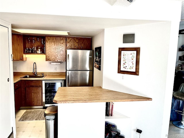 kitchen featuring beverage cooler, stainless steel fridge, kitchen peninsula, and sink