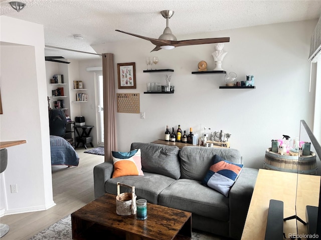 living room featuring indoor bar, a textured ceiling, ceiling fan, and light wood-type flooring