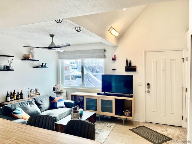 living room with ceiling fan, vaulted ceiling, a textured ceiling, and light wood-type flooring