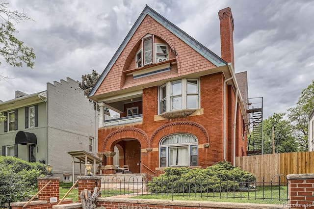 1343 Vine St, Denver, CO 80206 - view of front of property with a balcony, a fenced front yard, brick siding, and a chimney