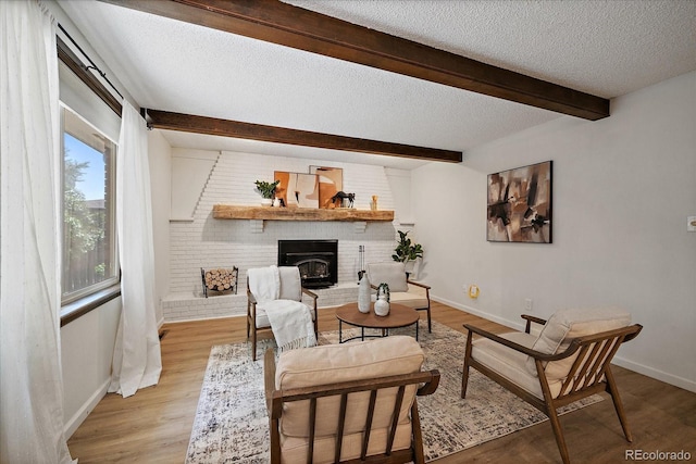 2130 Squires St, Longmont, CO 80501 - living room with a textured ceiling, beam ceiling, a brick fireplace, and light wood-style flooring