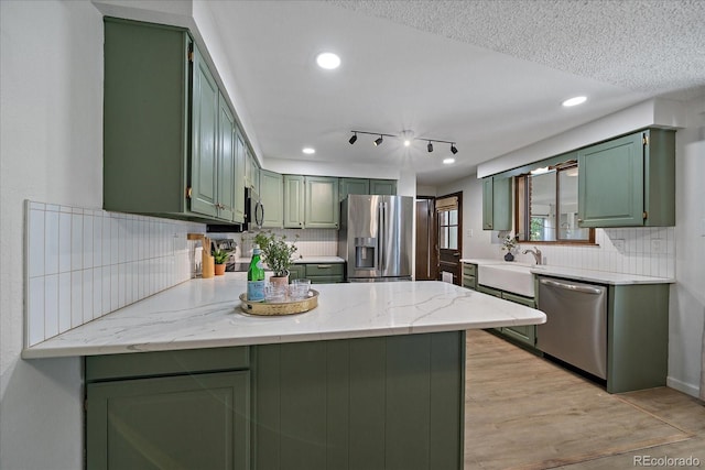 2130 Squires St, Longmont, CO 80501 - kitchen featuring green cabinets, appliances with stainless steel finishes, a peninsula, decorative backsplash, and recessed lighting