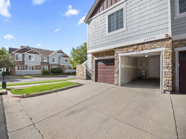 23500 E Alamo Pl Unit C, Aurora, CO 80016 - view of side of home with stone siding, an attached garage, concrete driveway, and board and batten siding