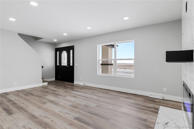 entryway with a high end fireplace and light hardwood / wood-style flooring