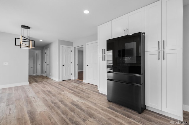 kitchen featuring black refrigerator, pendant lighting, white cabinets, and light hardwood / wood-style floors