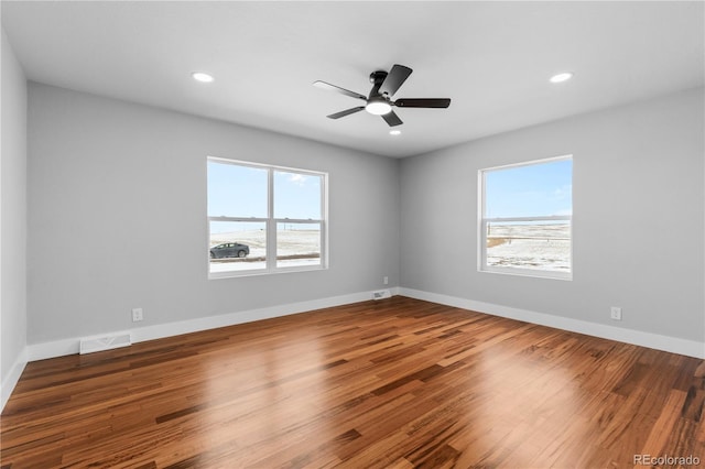 unfurnished room featuring ceiling fan, hardwood / wood-style flooring, and a healthy amount of sunlight