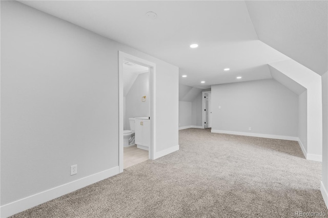 bonus room with vaulted ceiling and light carpet