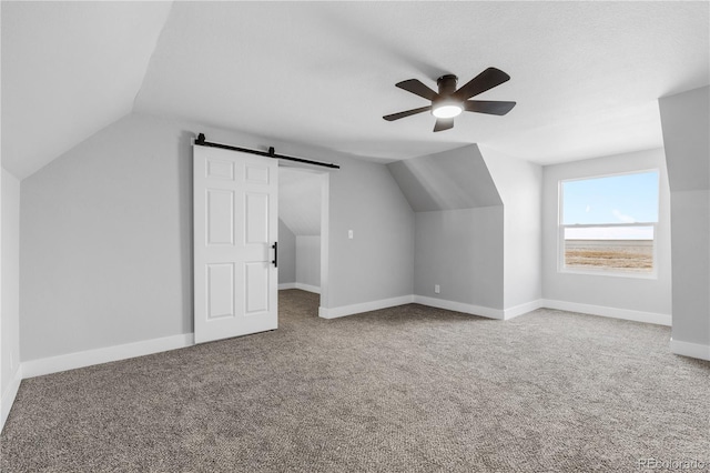 additional living space with a barn door, ceiling fan, lofted ceiling, and carpet flooring