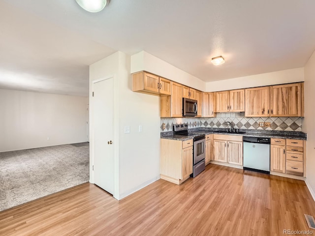 kitchen featuring stainless steel appliances, sink, light wood-type flooring, and decorative backsplash