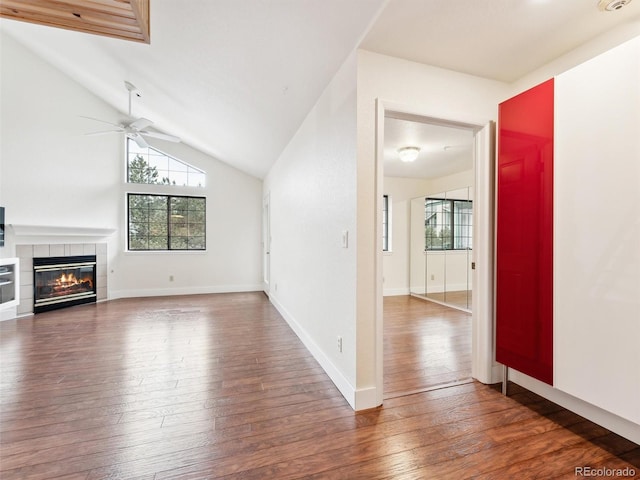 unfurnished living room with a tile fireplace, ceiling fan, dark hardwood / wood-style flooring, and lofted ceiling