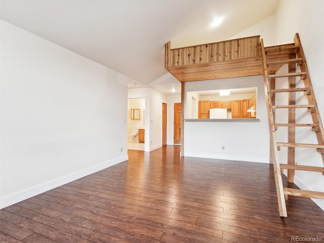 unfurnished living room with high vaulted ceiling and dark wood-type flooring