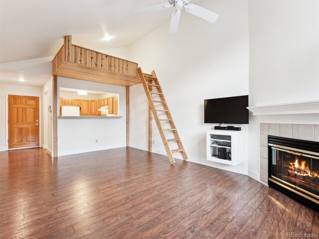 unfurnished living room with a tile fireplace, ceiling fan, dark hardwood / wood-style flooring, and vaulted ceiling