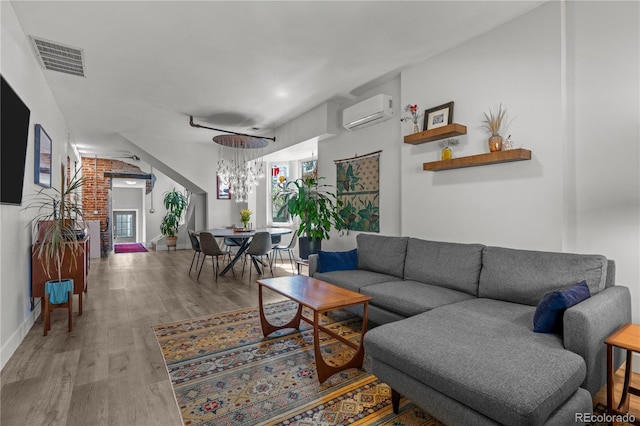 living area featuring a wall mounted air conditioner, wood finished floors, baseboards, and a chandelier