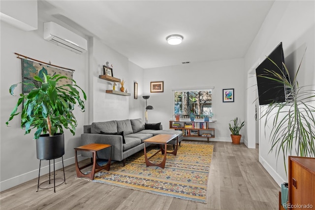 living room featuring a wall mounted air conditioner, wood finished floors, and baseboards