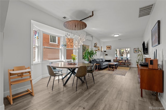 dining space with wood finished floors, a wall mounted AC, a chandelier, and baseboards