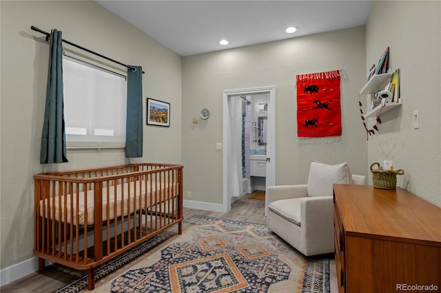 bedroom with light wood-type flooring, baseboards, and a nursery area