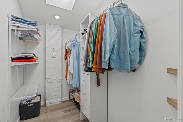 walk in closet with wood finished floors and a skylight