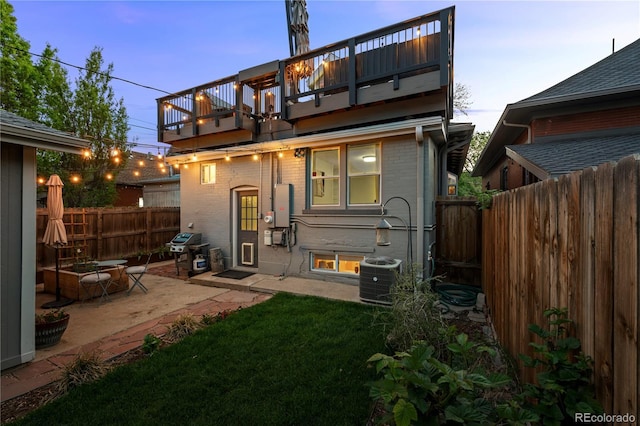 rear view of house featuring a balcony, central AC, a patio area, and brick siding