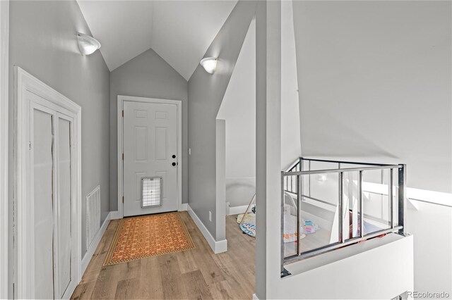 entryway with light wood-style floors, lofted ceiling, and baseboards