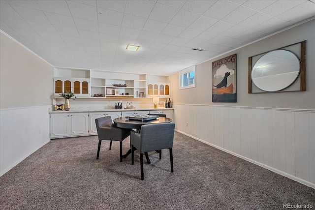 dining room with built in shelves, carpet floors, and crown molding