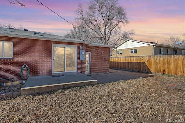 back house at dusk featuring a patio