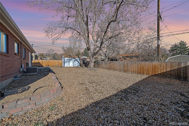 yard at dusk with cooling unit and a shed